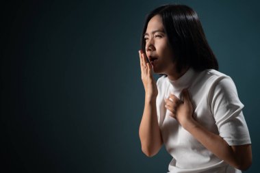 Asyalı kadın boğazı ağrıyordu ve mavi arka planda tek başına duruyordu. Sağlık hizmetleri kavramları.