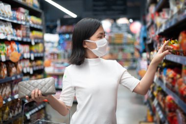 Korumalı yüz maskesi takan Asyalı bir kadın mağazada virüs ve kirlilik süpermarketten yiyecek alıyor. Corona Virüsü COVID-19 ile yeni yaşam tarzı.