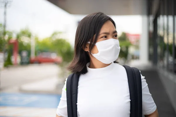 Asian woman happy smiling wearing protective face mask prevention virus and pollution, walking to department store for shopping. New lifestyle with Corona Virus COVID-19.