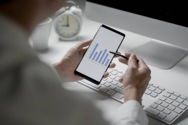 Ofiste çalışan işadamlarının yakın plan çekimleri. Akıllı telefon tutup diyagramları kontrol ediyorlar.