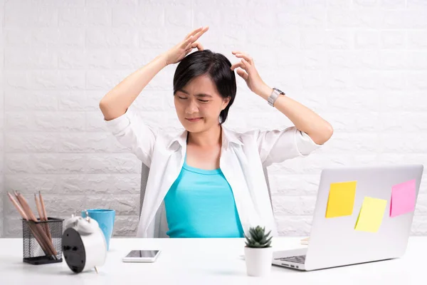 Woman scratching her head at office