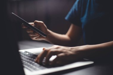 Bilgisayarda arama yapmak ve akıllı telefon tutmak için mesaj yazan ellerin yakın çekim görüntüsü. Alçak tuş.