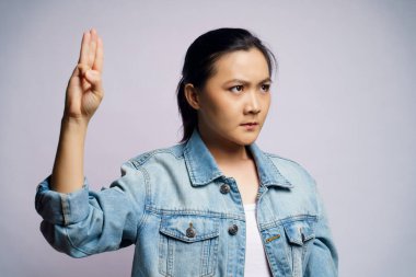 Beyaz arka planda üç parmak gösteren Asyalı bir kadın..