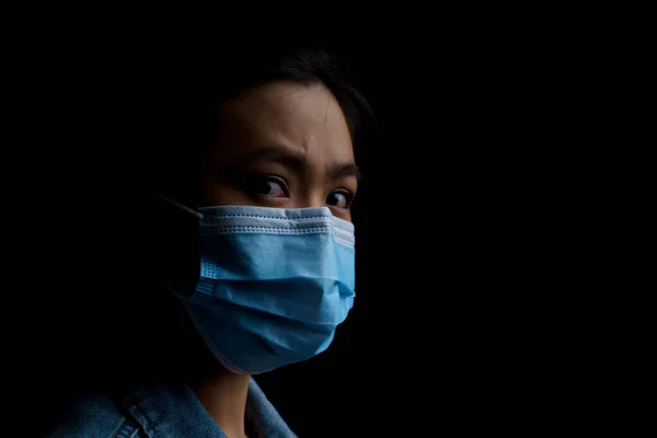 Asian woman wearing protective mask isolated on background. Low key.