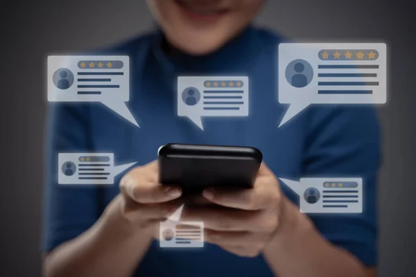 Geri bildirim için akıllı telefon kullanan Asyalı kadın yorum ikonu hologram efektli yorumlar yapıyor. Arkaplanda izole.