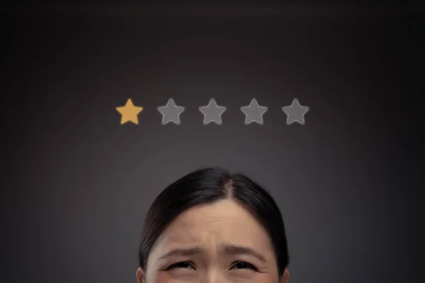 Close up shot of unhappy Asian woman and star icon hologram effect.