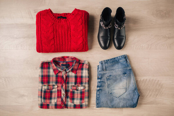flat lay of woman style and accessories, red knitted sweater, checkered shirt, denim jeans, black leather boots, autumn fashion trend, view from above, clothes