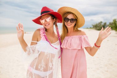iki güzel stil kadın sahilde tatilde, yaz stili, moda trendi, gülümseyen, mutlu, hasır şapka takan, güneş gözlüğü takan, moda modası, pembe ve dantel elbise, seksi kıyafet