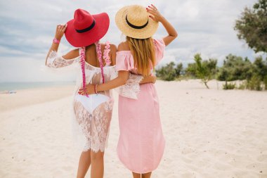 Sahilde tatilde olan iki güzel kadının manzarası, yaz stili, moda modası, hasır şapkalar, moda modası, pembe ve dantel elbise, seksi kıyafetler.