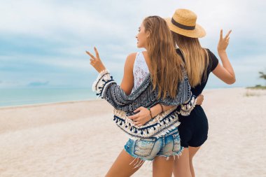 Plajda yaz tatilinde şık, güzel kadınlar, bohem tarzı, arkadaşlar birlikte, moda trendi, aksesuarlar, mutlu duygu, olumlu ruh hali, kucaklama, arkadan görünüm, seyahat, şort, seksi