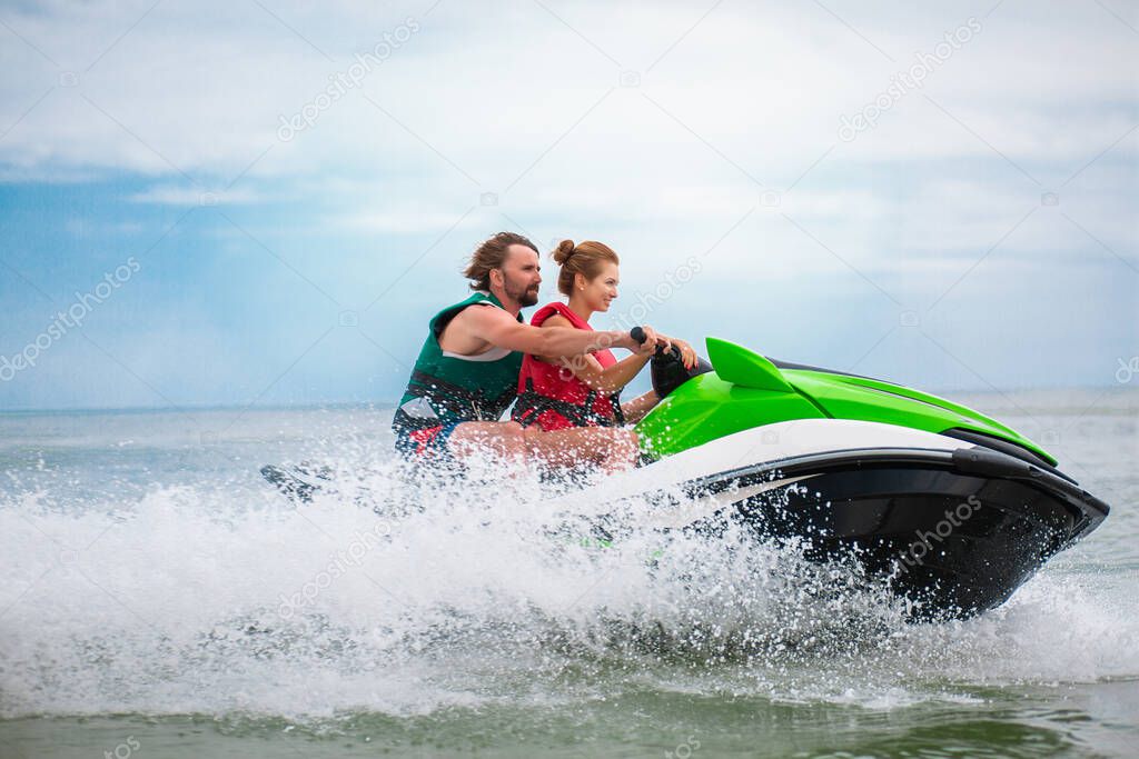 young people having fun driving on high speed on water scooter, man and woman on summer vacation, friends doing active sport