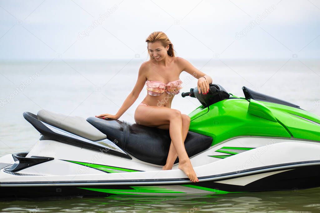 young attractive woman with slim sexy body in stylish bikini swimsuit having fun on water scooter, summer vacation, active sport