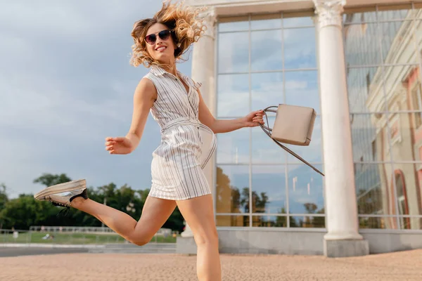 穿着夏装风格的白色连衣裙 戴着太阳镜和手提包 穿着运动鞋在城市街道上跑来跑去 很滑稽 — 图库照片