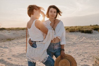 Tropik plajlarda yaz tatilinde şık güzel kadınlar, bohem stili, birlikte arkadaşlar, moda aksesuarları, kot pantolon, hasır şapka, eğlenmek.