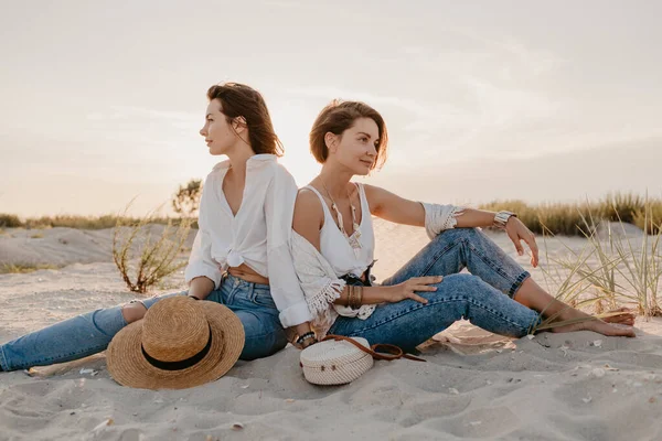 Tropik plajlarda yaz tatilinde şık güzel kadınlar, bohem stili, birlikte arkadaşlar, moda aksesuarları, kot pantolon, hasır şapka, eğlenmek.