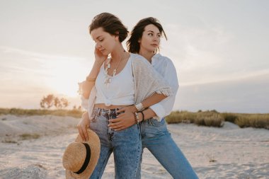 Tropik plajlarda yaz tatilinde şık güzel kadınlar, bohem stili, birlikte arkadaşlar, moda aksesuarları, kot pantolon, hasır şapka, eğlenmek.