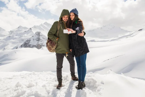 年轻漂亮的嬉皮士夫妇在山上远足 寒假旅行 恋爱中的男人 浪漫的女人 温暖的衣服 Anorak 牛仔裤 用智能手机拍自拍照 — 图库照片