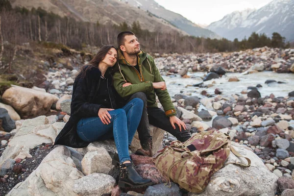 年轻漂亮的嬉皮士情侣恋爱中 坐在河边 徒步旅行 一起旅行 保暖衣服 — 图库照片