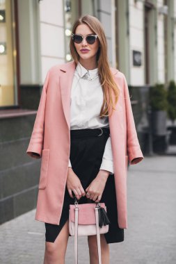 Çekici, şık, güler yüzlü, şehir caddesinde pembe ceketli, bahar moda çantalı, zarif tarzda, güneş gözlüğü takan bir kadın.