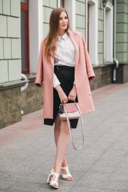 Çekici, şık, gülümseyen bir kadın pembe ceketli, şehir caddesinde yürüyor bahar moda çantası, zarif bir tarzı var.
