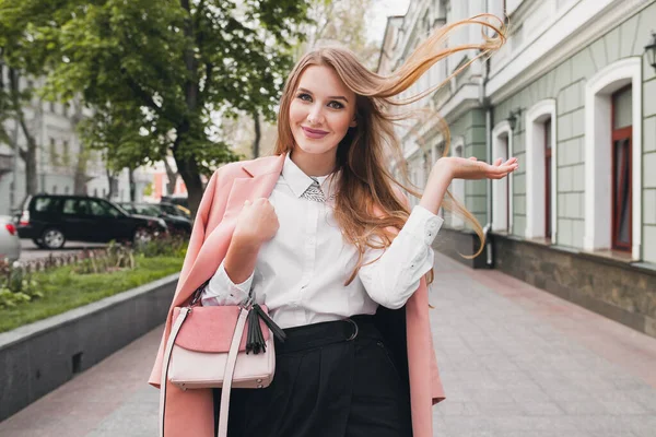 매력적 미소짓는 여자가 분홍색 코트를 지갑을 스타일로 머리를 흔들며 거리를 — 스톡 사진