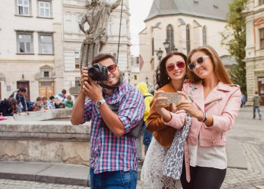 Genç hippi arkadaş grubu seyahat ediyor, klasik tarz, Avrupa tatili, güneş gözlüğü, eski şehir merkezi, mutlu ruh hali, gülümsüyor, kucaklıyor, fotoğraf çekiyor, akıllı telefondan selfie çekiyor.