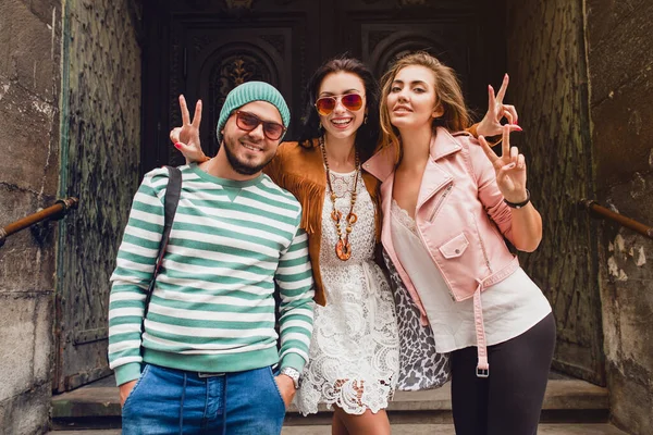 young hipster company of friends traveling, vintage style, europe vacation, sunglasses, old city center, happy positive mood, smiling, embracing, pointing finger, looking forward