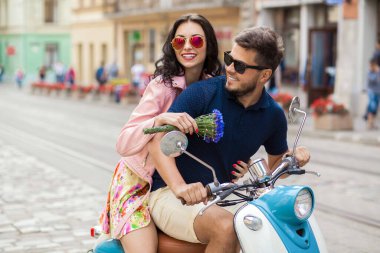 Genç, güzel, hippi bir çift motosikletle şehir caddesinde, yaz tatilinde, seyahat ederken, romantizm yaparken, gülümserken, mutluyken, eğlenirken, güneş gözlüğü takarken, şık giyinirken, aşkta, maceralarda, randevuda...