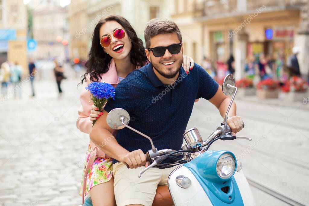 young beautiful hipster couple riding on motorbike city street, summer europe vacation, traveling, romance, smiling, happy, having fun, sunglasses, stylish outfit, together in love, adventures, date