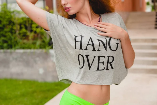young stylish woman in fitness apparel, ginger hair, green shorts, sunglasses, oversize t-shirt, hang over, party mood. having fun, sexy, hot, flirty, slim body, athletic,