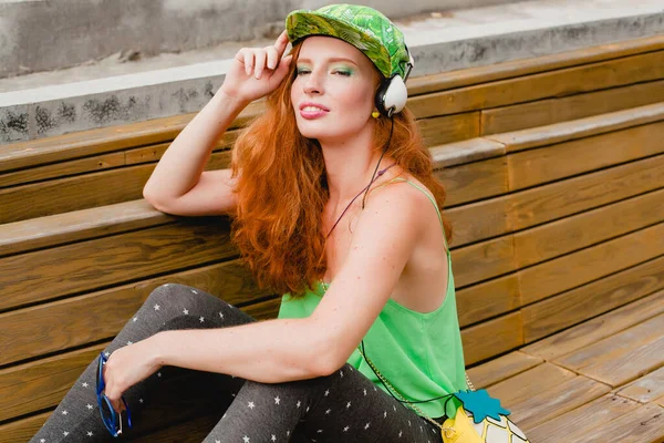 若いスタイリッシュなヒップスター幸せな生姜の女性は 音楽を聞いて ヘッドフォン 緑のキャップ 面白い顔を閉じて 楽しい クレイジーな気分 都市スタイルを持っている — ストック写真