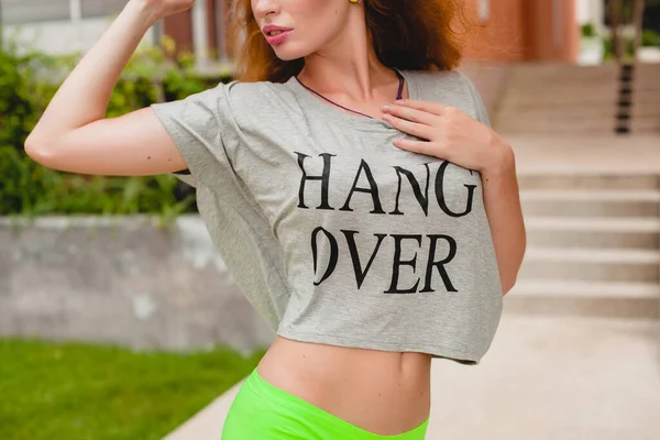 young stylish woman in fitness apparel, ginger hair, green shorts, sunglasses, oversize t-shirt, hang over, party mood. having fun, sexy, hot, flirty, slim body, athletic,