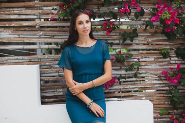 Mavi elbiseli genç, şık güzel bir kadın, yaz modası trendi, tatil, bahçe, tropik otel terası, gülümseme