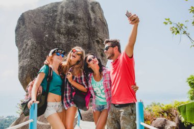Mutlu hipster arkadaş grubu dünyayı geziyor, geziyor, güzel kıyafetler, çılgın, eğleniyor, gülüyor, gülümsüyor, tropikal tatil yapıyor, öğrenciler, güneş gözlükleri, akıllı telefondan selfie çekiyor.