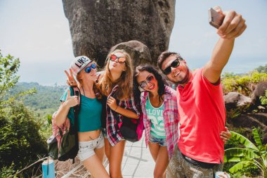 Mutlu hipster arkadaş grubu dünyayı geziyor, geziyor, güzel kıyafetler, çılgın, eğleniyor, gülüyor, gülümsüyor, tropikal tatil yapıyor, öğrenciler, güneş gözlükleri, akıllı telefondan selfie çekiyor.