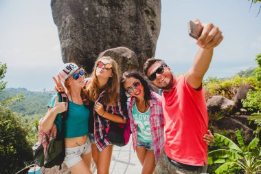 Mutlu hipster arkadaş grubu dünyayı geziyor, geziyor, güzel kıyafetler, çılgın, eğleniyor, gülüyor, gülümsüyor, tropikal tatil yapıyor, öğrenciler, güneş gözlükleri, akıllı telefondan selfie çekiyor.