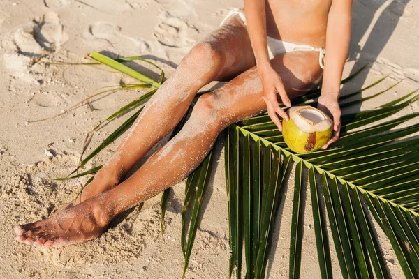 熱帯のビーチで若い美しい女性 タイの夏休み ココナッツを飲みます スリムなセクシーなボディ 日焼けした肌 ヤシの木の葉に座って 足を閉じます — ストック写真