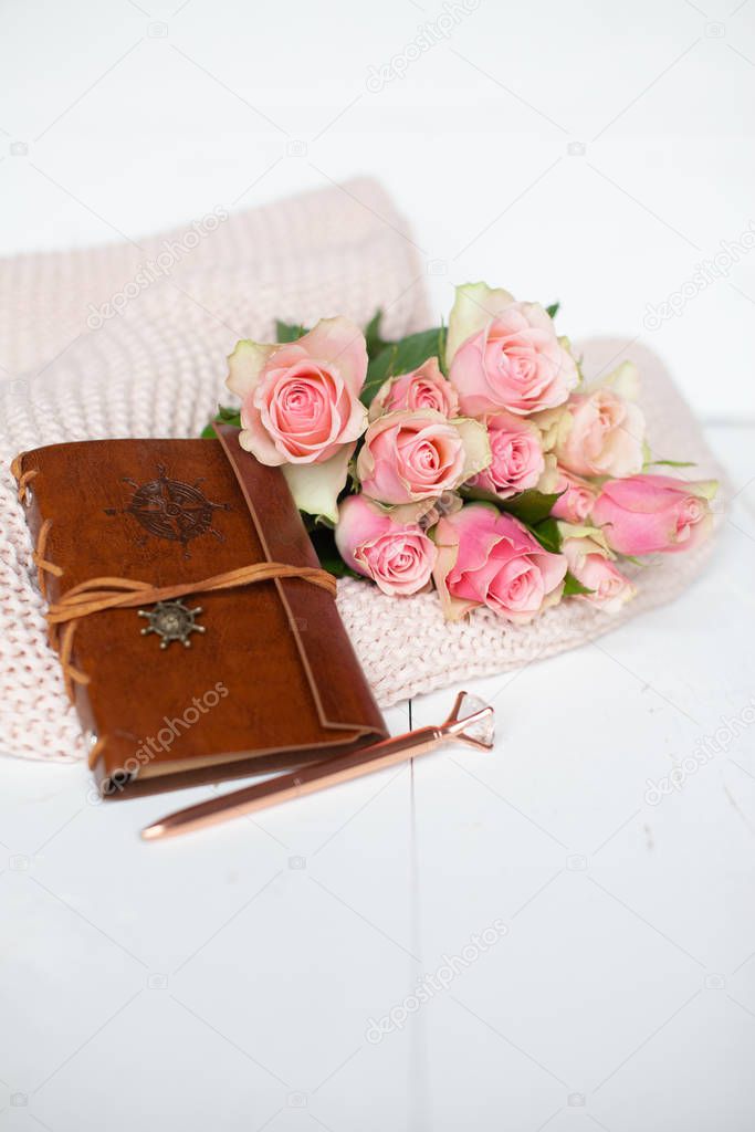 Pink roses and a leather notebook on a pink blanket