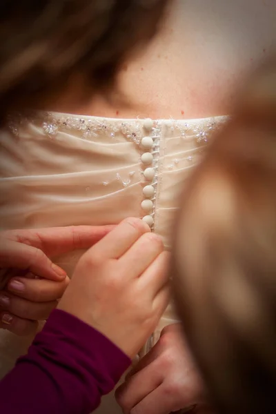 Подружка невесты шнурует белое свадебное платье для невесты . — стоковое фото