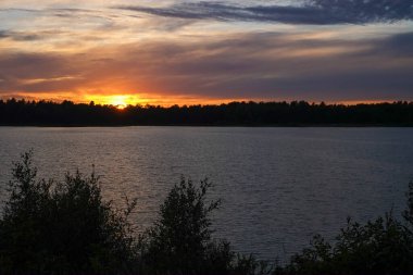 Orman gölünün üzerinde dramatik bir gün batımı