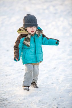 Kışın karla oynayan çocuk. 