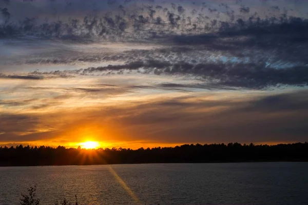 Драматический закат над лесным озером — стоковое фото