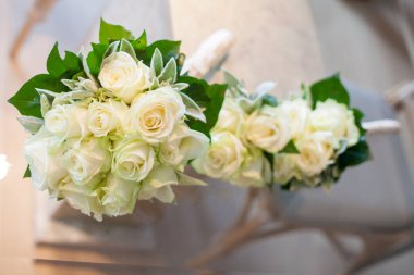 Güzel beyaz gül buketleri sanatsal olarak yeşillikle sıralanmış, düğünler veya özel günler için mükemmel.