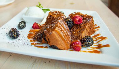 Dondurma, karamel sos ve çilek çikolata bisküvi parçaları. Karamel, ahududu ve böğürtlen ile kek. Dondurma nane ile bırakır. Masa lambası tatlı bir tabak.