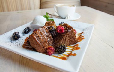 Dondurma, karamel sos ve çilek çikolata bisküvi parçaları. Karamel, ahududu ve böğürtlen ile kek. Dondurma nane ile bırakır. Masa lambası tatlı bir tabak.