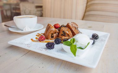 Dondurma, karamel sos ve çilek çikolata bisküvi parçaları. Karamel, ahududu ve böğürtlen ile kek. Dondurma nane ile bırakır. Masa lambası tatlı bir tabak.