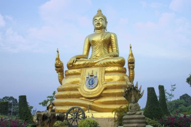 Altın Buda heykeli. Bahçede güzel dini heykel açık bulutlu gökyüzünün arka planı.