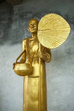 Altın aziz heykeli. Aziz adam dev bir sıçrama tutuyor. Gri duvar arka planda güzel altın dini heykel. Bir Budist tapınağının restorasyonu.