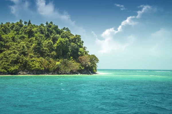 Beautiful paradise green island in the ocean. Tropics. Thailand Andaman Sea. Seascape with azure water and an island with many plants.