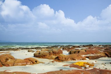 Okyanusta düşük gelgit zamanında tropikal adanın kıyıları. Masmavi su, sualtı taşları ve beyaz mercan kumu ile Seascape. Tayland. Andaman Denizi.